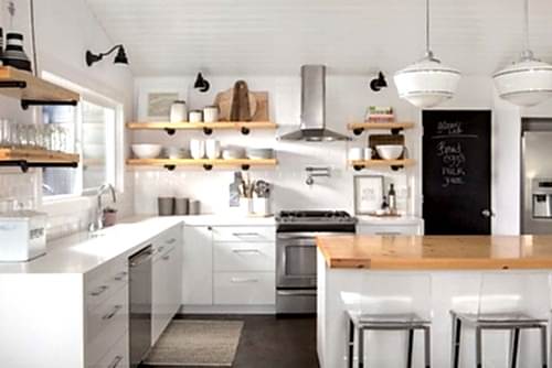 A kitchen with white cabinets and wooden counters.
