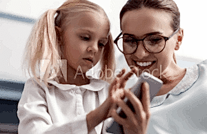 A woman and girl looking at something on the phone.