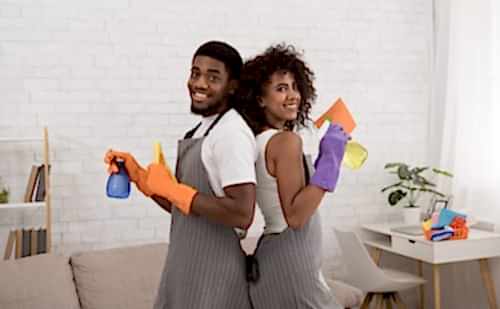 A man and woman holding cleaning supplies in their hands.